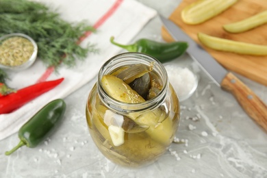 Photo of Jar with pickled cucumbers on grey table
