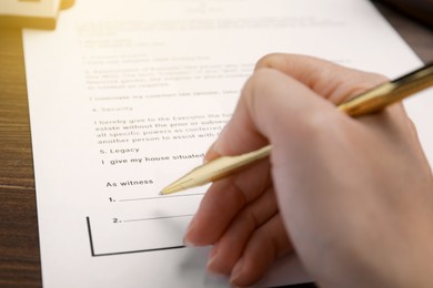 Woman signing Last Will and Testament at table, closeup