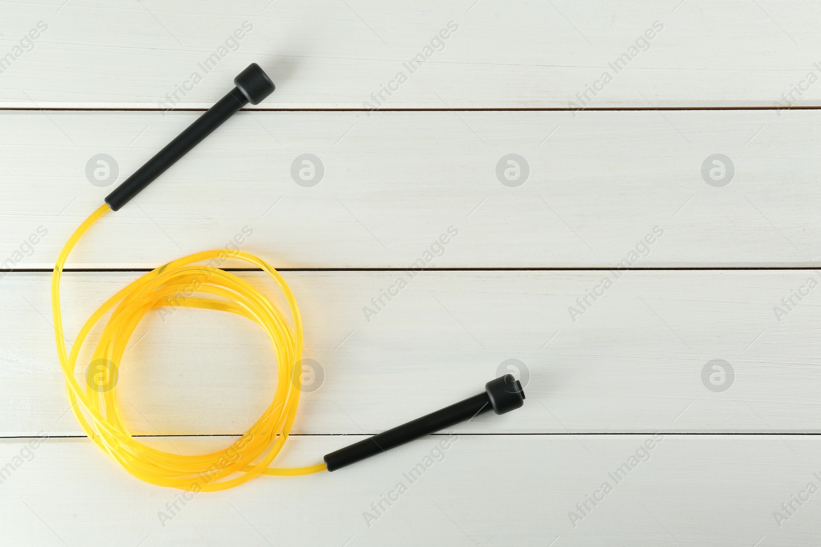 Photo of Skipping rope on white wooden table, top view. Space for text