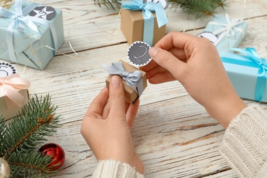 Photo of Woman making advent calendar at white wooden table, closeup