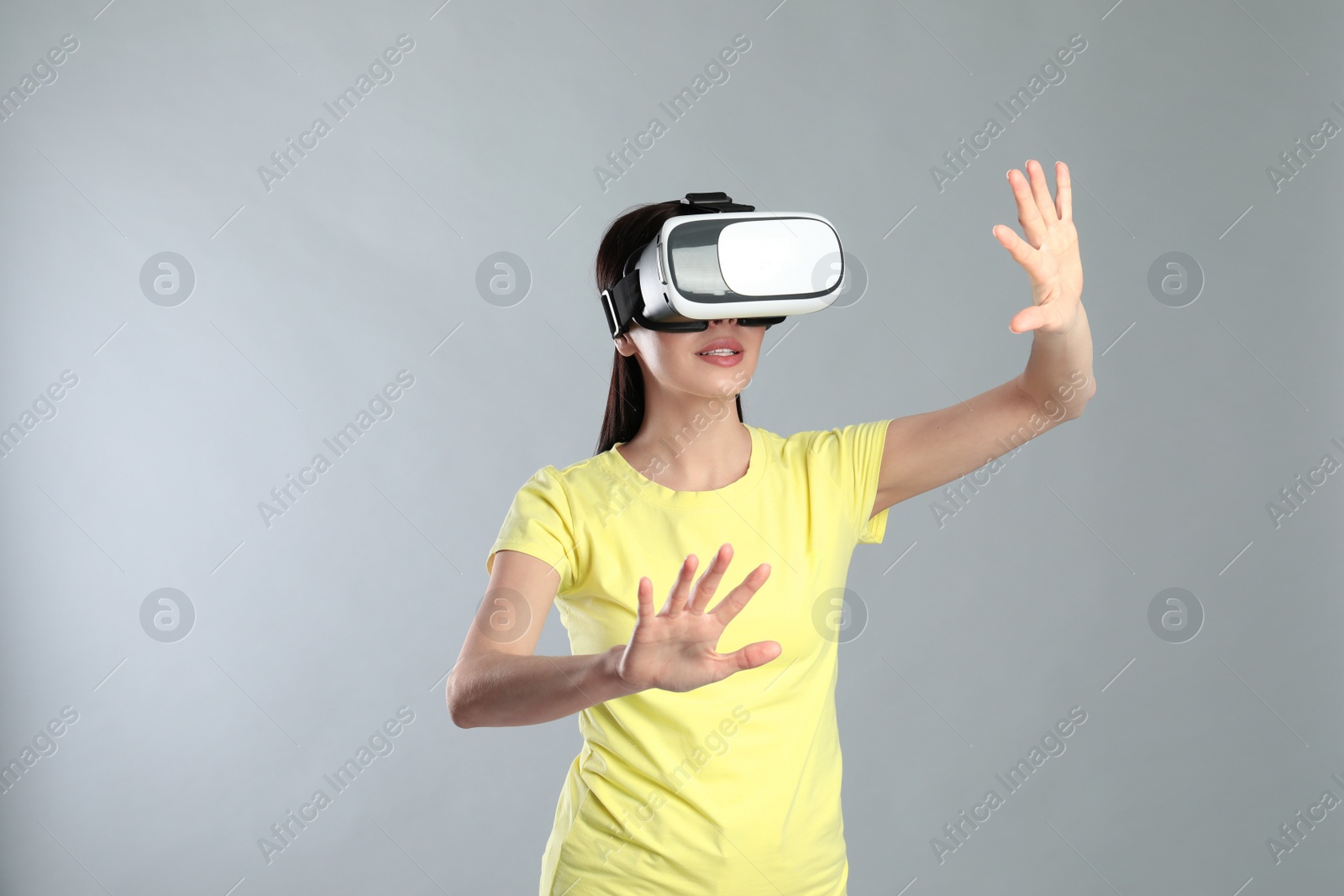 Photo of Woman using virtual reality headset on grey background