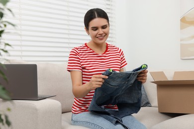 Young woman with just unpacked new jeans at home. Online shopping