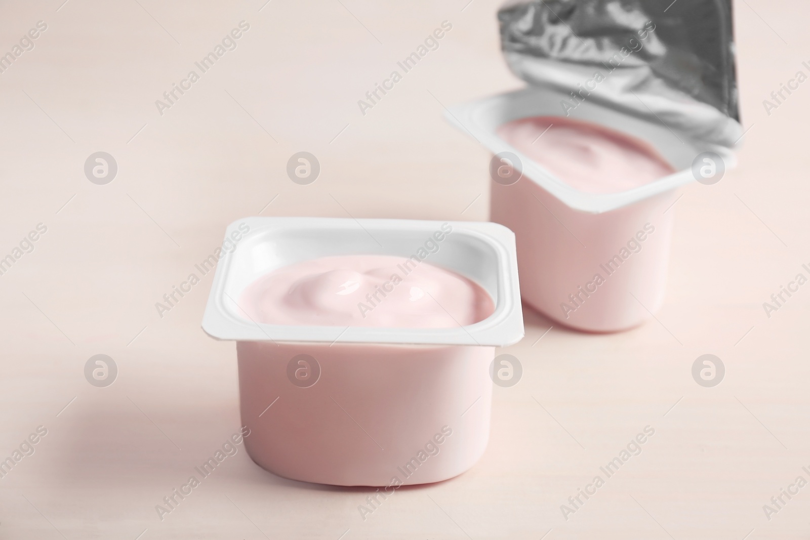 Photo of Plastic cups with yummy yogurt on wooden table