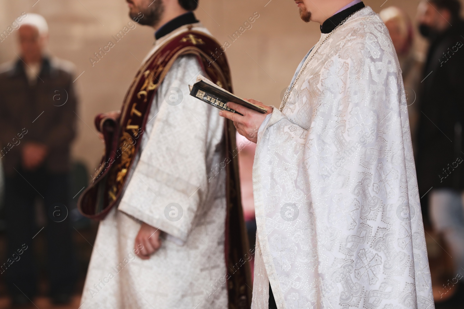 Photo of MYKOLAIV, UKRAINE - FEBRUARY 27, 2021: Priest with ecclesiastical book conducting baptism ceremony in Kasperovskaya icon of Mother of God cathedral, closeup
