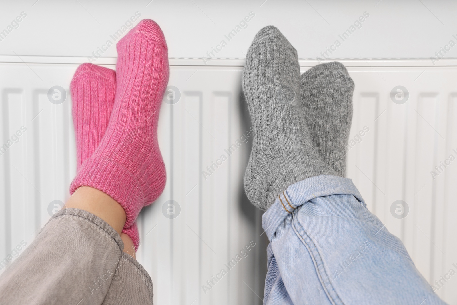 Photo of People warming feet near heating radiator, closeup