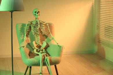 Waiting concept. Human skeleton sitting in armchair indoors, space for text