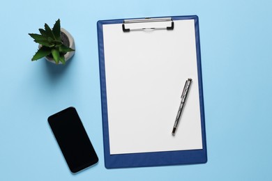 Ballpoint pen, clipboard with paper sheet and smartphone on light blue background, flat lay