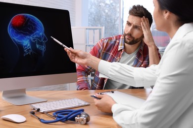 Photo of Neurologist showing brain scan to sad man in clinic