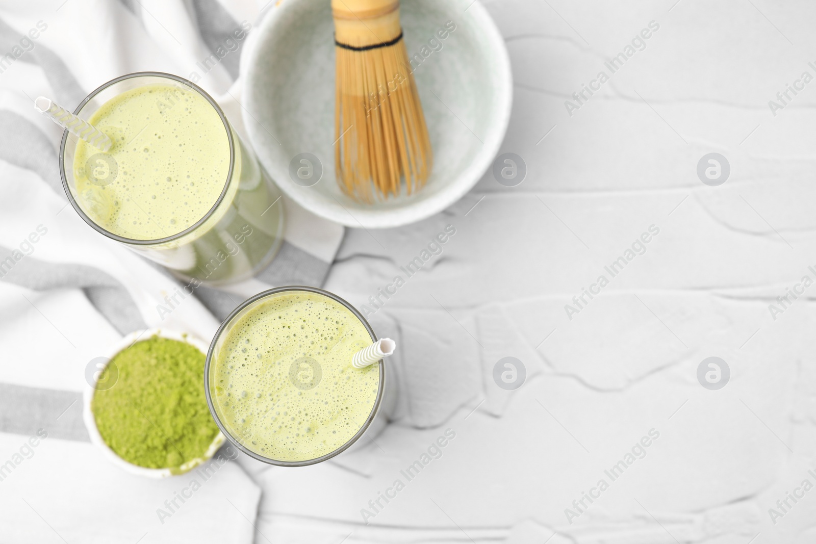 Photo of Glasses of tasty matcha smoothie on white textured table, flat lay. Space for text