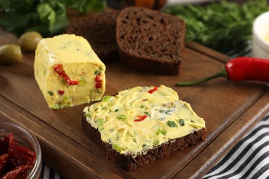 Photo of Tasty butter with green onion, chili pepper and rye bread on table, closeup