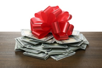 Photo of Pile of dollar bills with red bow on wooden table against white background
