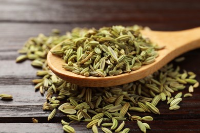 Photo of Spoon with fennel seeds on wooden table, closeup