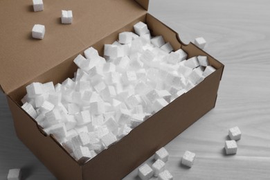 Cardboard box and styrofoam cubes on wooden floor