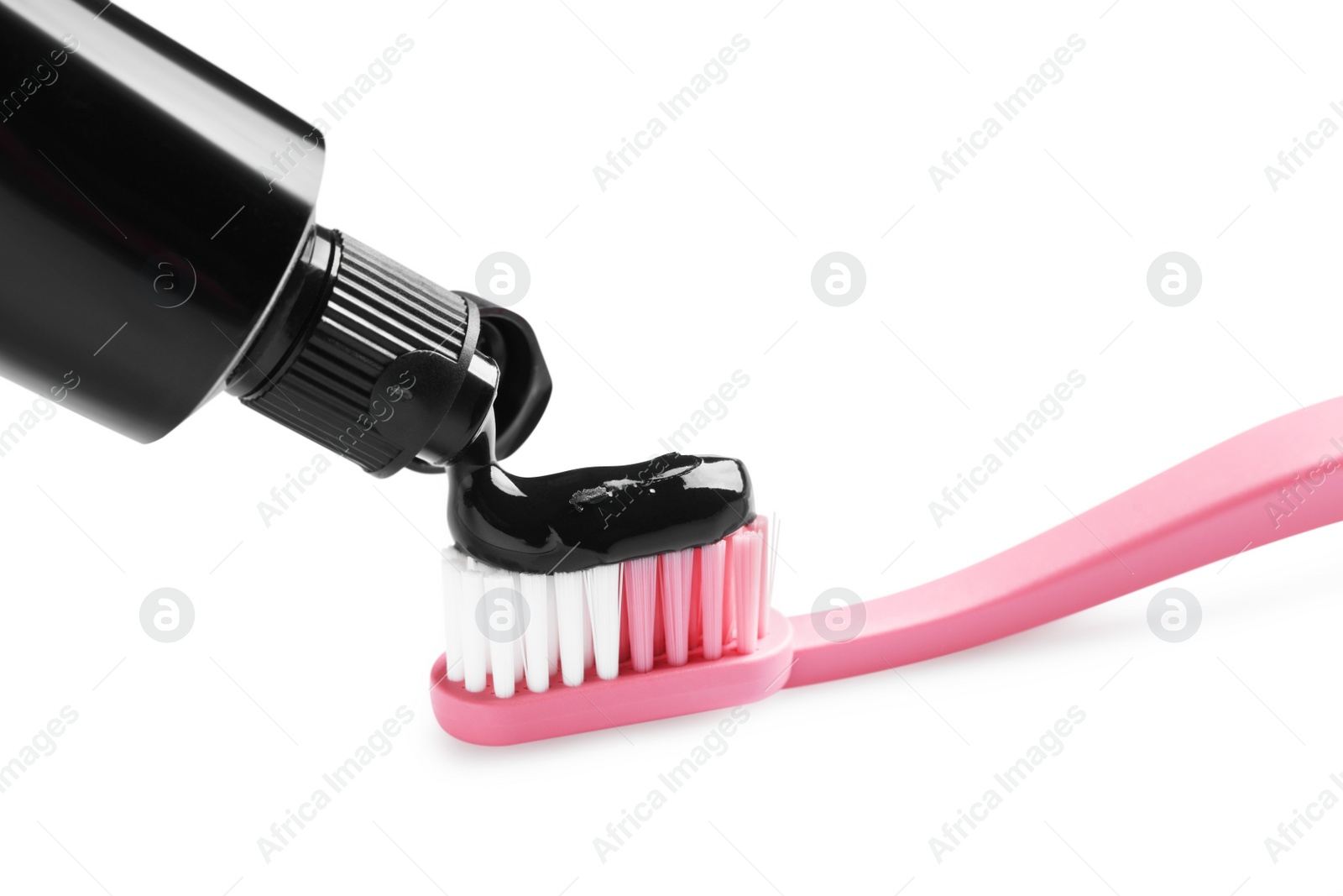 Photo of Tube of charcoal toothpaste and brush on white background