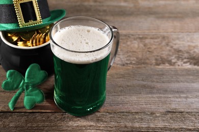 Photo of St. Patrick's day celebration. Green beer, leprechaun hat, pot of gold and decorative clover leaf on wooden table. Space for text