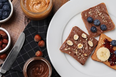 Different tasty toasts with nut butter and products on table, flat lay