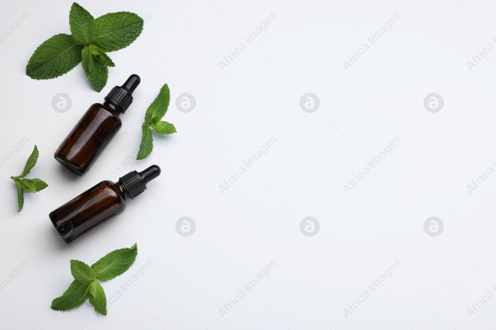 Photo of Bottles of essential oil and mint on white background, flat lay. Space for text