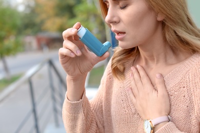 Photo of Woman using asthma inhaler outdoors, closeup. Health care