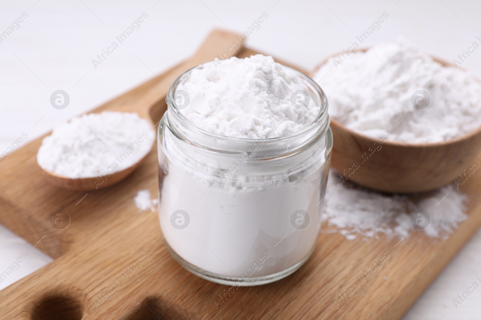 Photo of Jar and spoon of starch on wooden board, closeup