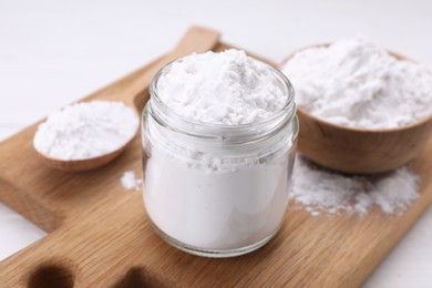 Photo of Jar and spoon of starch on wooden board, closeup