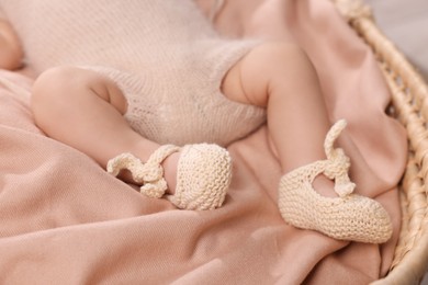 Photo of Newborn baby lying on blanket in wicker crib, closeup