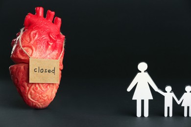 Photo of Divorce concept. Heart model, card with word Closed near paper figures of woman and children on black background