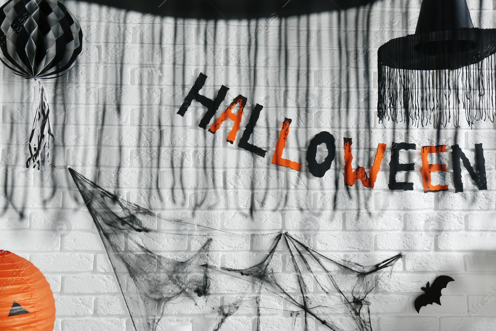 Photo of Word Halloween made of colorful letters and festive decor on brick wall