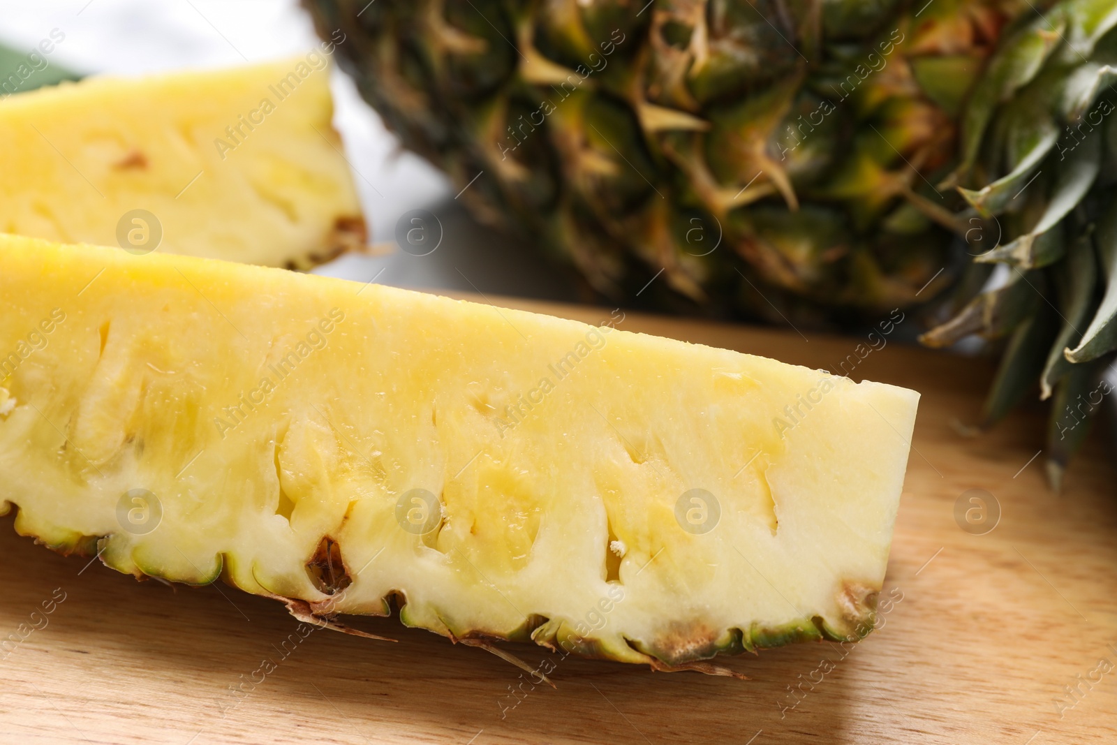 Photo of Wooden board with cut tasty ripe pineapple on table, closeup