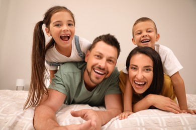 Photo of Happy family taking selfie on bed at home