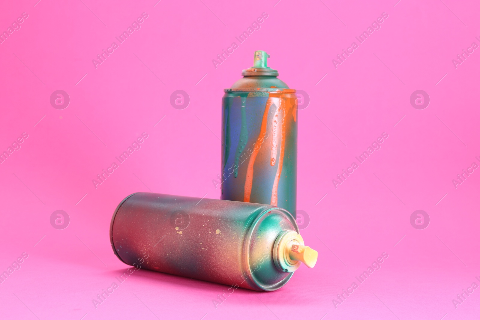 Photo of Two spray paint cans on pink background