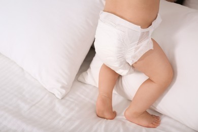 Cute baby in dry soft diaper on white bed, closeup