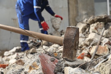 Sledgehammer on pile of broken stones. Man working outdoors, selective focus