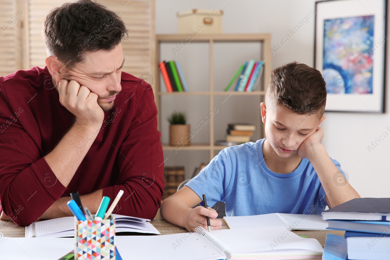 Photo of Dad helping his son with difficult homework assignment in room