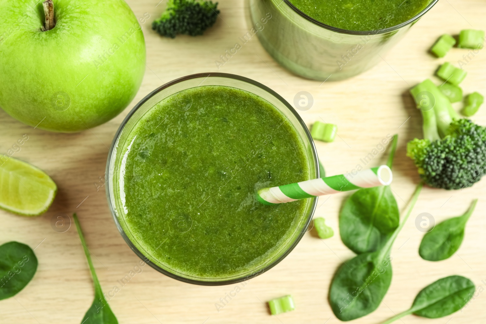 Photo of Delicious green juice and fresh ingredients on wooden table, flat lay