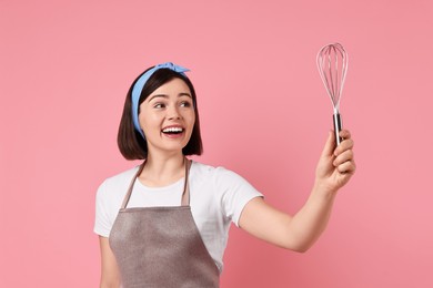 Happy confectioner with whisk on pink background