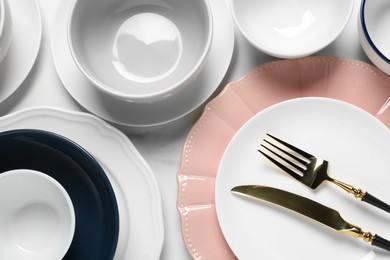 Beautiful ceramic dishware and cutlery on white table, flat lay