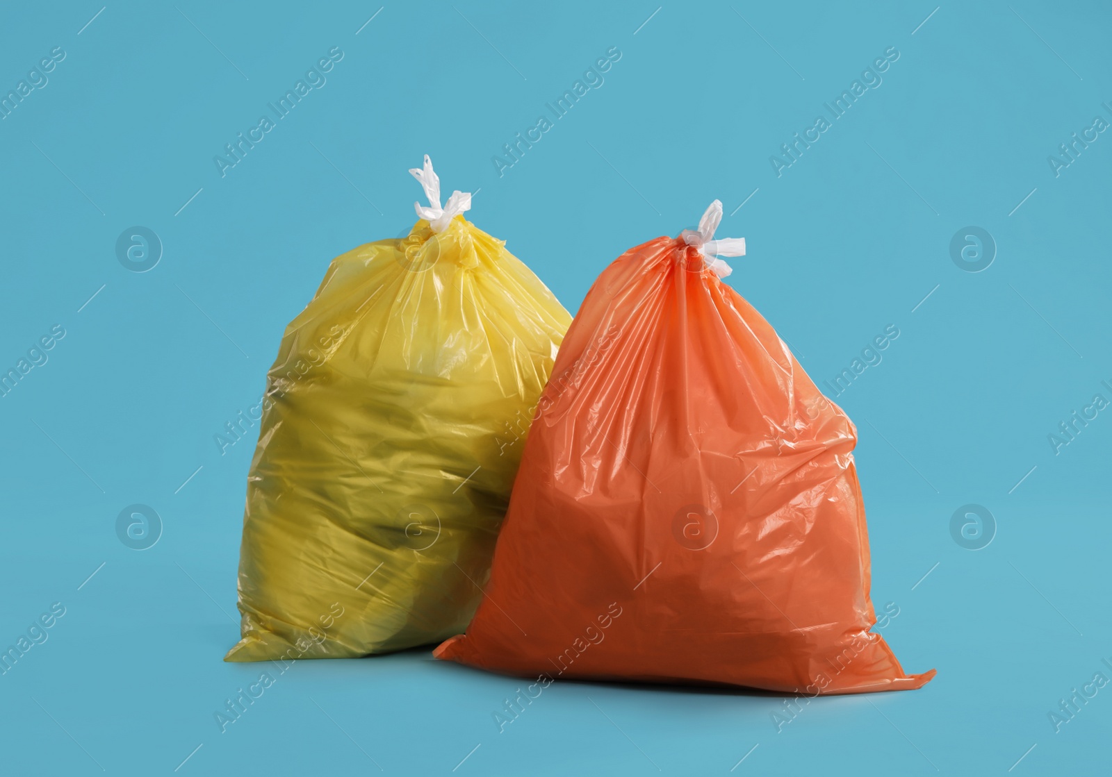 Photo of Trash bags full of garbage on light blue background