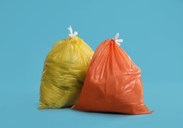 Trash bags full of garbage on light blue background