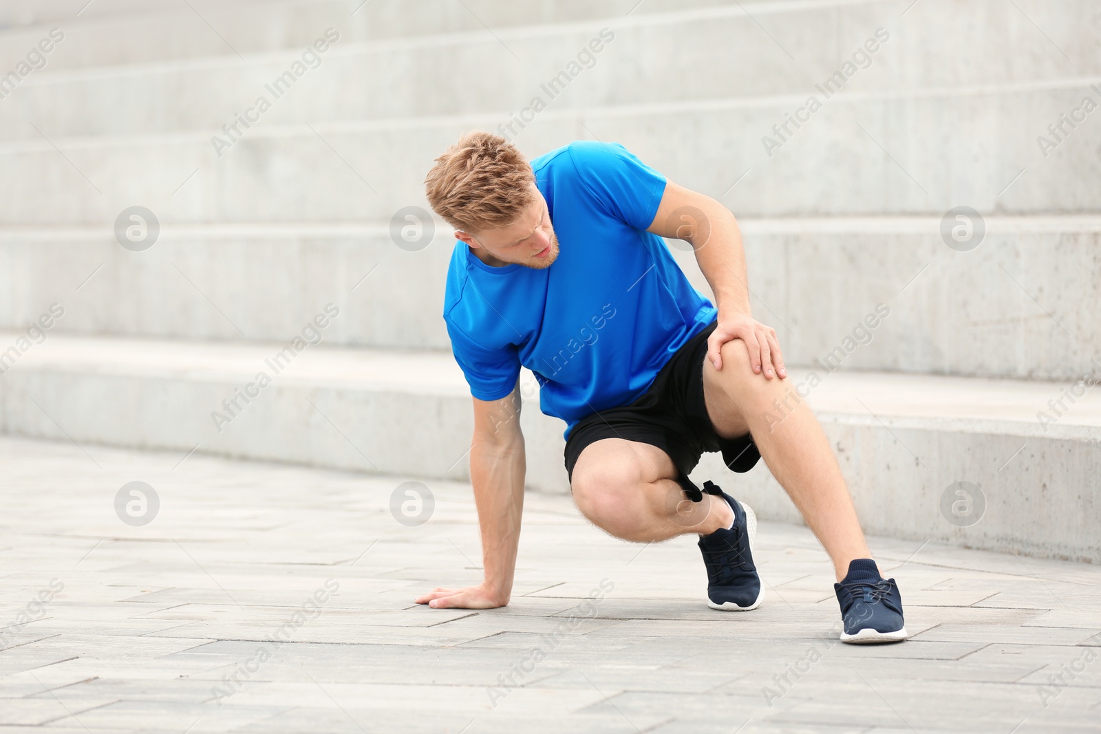 Photo of Man in sportswear suffering from knee pain on stairs