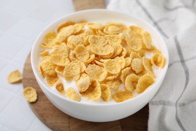 Photo of Breakfast cereal. Tasty corn flakes with milk in bowl on white table, closeup