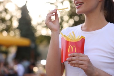 Lviv, Ukraine - September 26, 2023: Woman with McDonald's french fries outdoors, closeup. Space for text