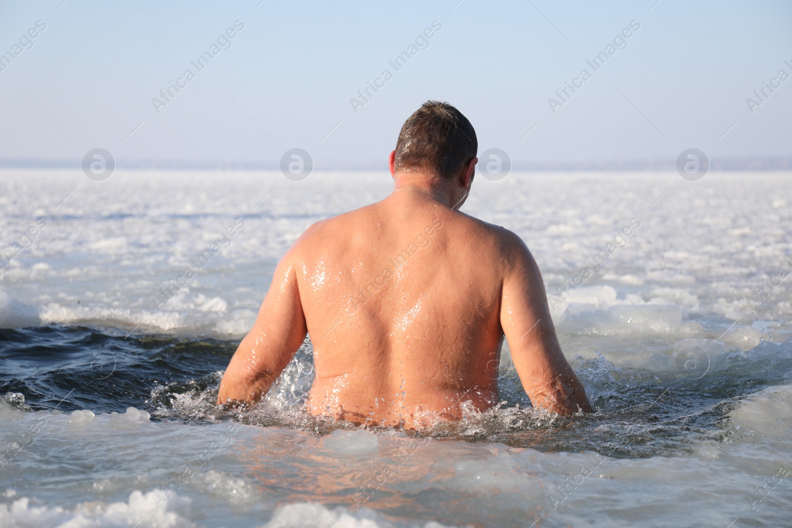 Photo of MYKOLAIV, UKRAINE - JANUARY 06, 2021: Man immersing in icy water on winter day, back view