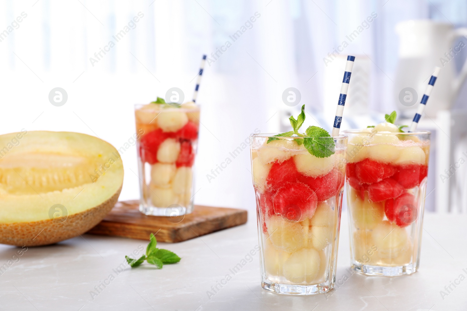 Photo of Glasses with tasty melon and watermelon ball drink on light table