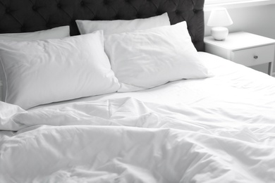 Photo of Comfortable bed with white linen and pillows at home