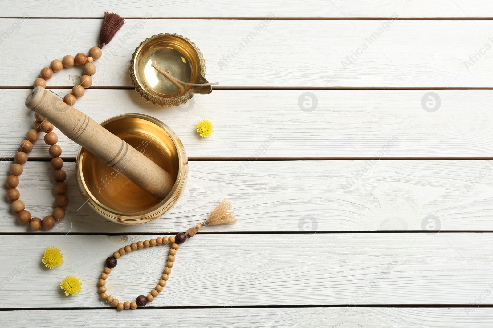 Photo of Flat lay composition with golden singing bowl on white wooden table, space for text. Sound healing