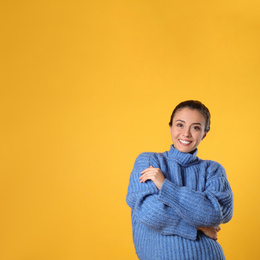 Young woman in stylish blue sweater on yellow background, space for text