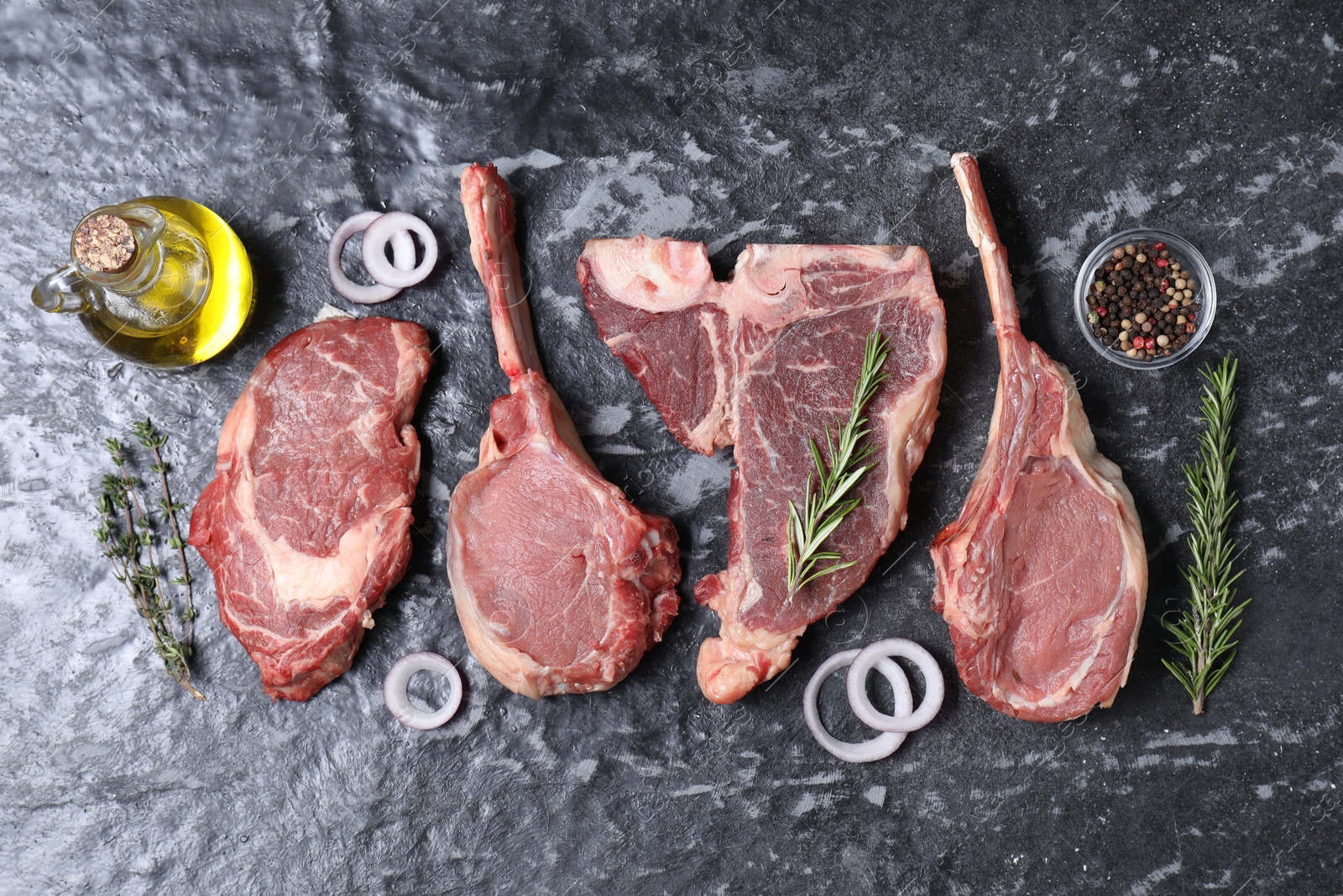 Photo of Fresh raw beef cuts and different spices on grey textured table, flat lay