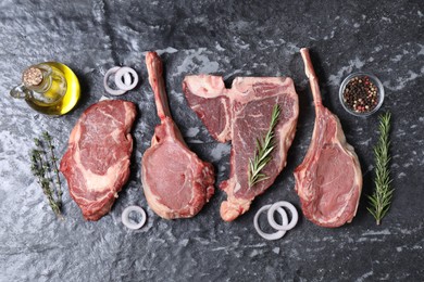 Fresh raw beef cuts and different spices on grey textured table, flat lay