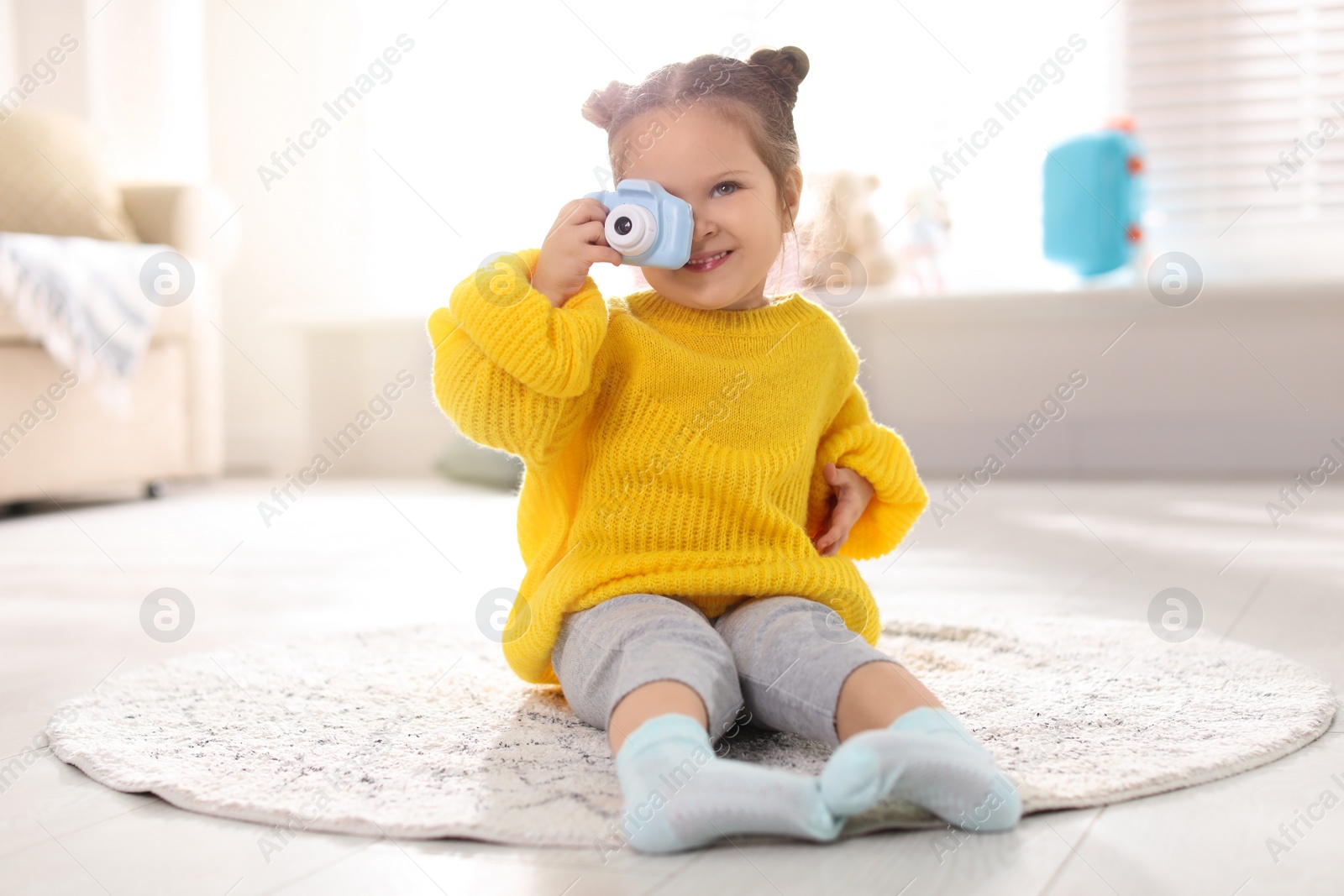Photo of Little photographer taking picture with toy camera at home