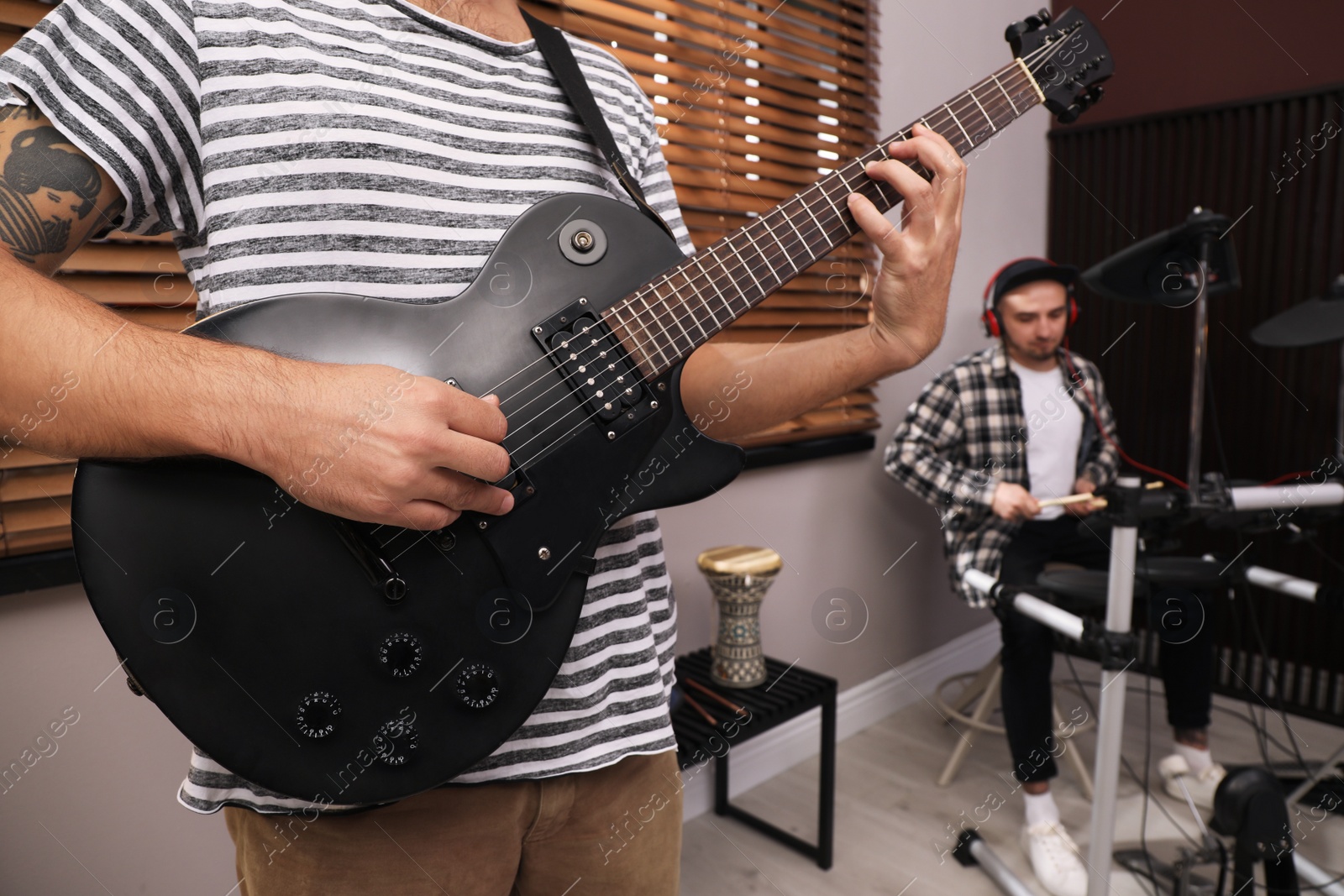 Photo of Man playing electric guitar during rehearsal in studio, closeup. Music band practice